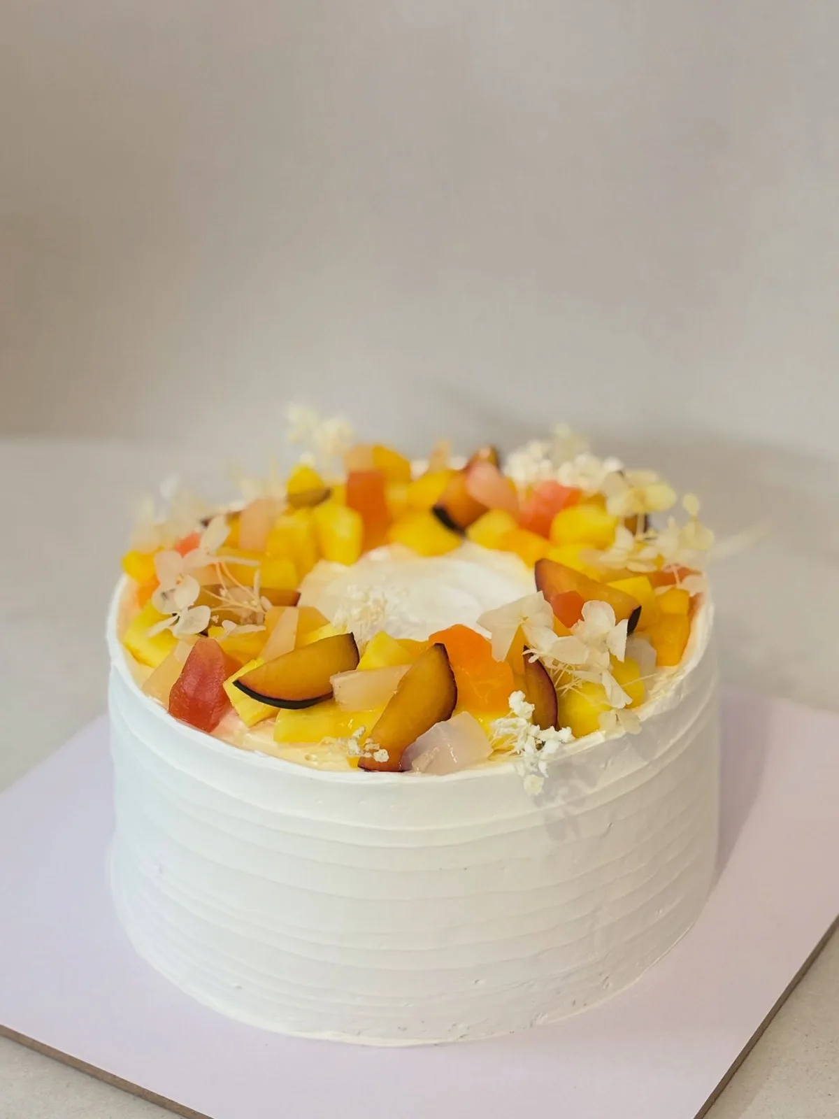 Fresh cream cake topped with mango, peach and seasonal fruit