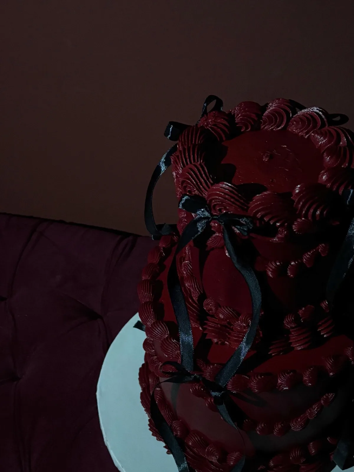 Deep maroon cake with piped shells and black ribbon detailing