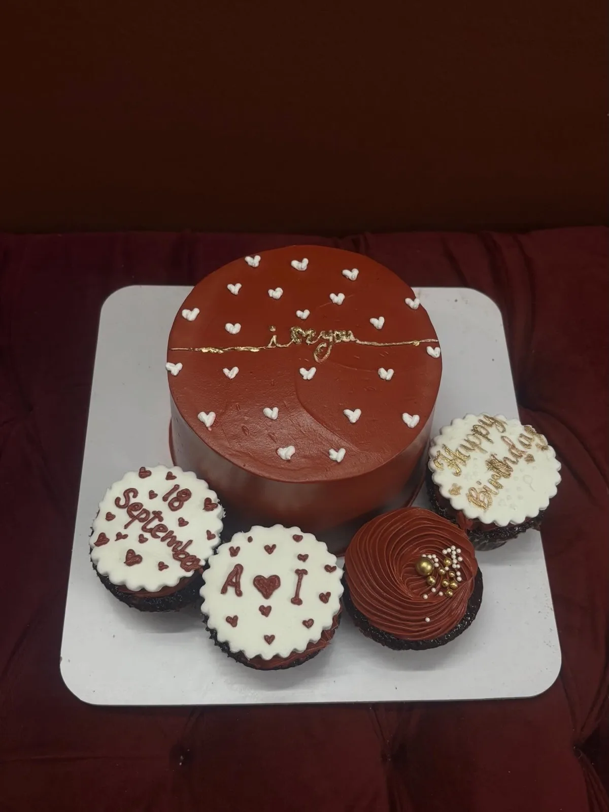 Red velvet celebration cake with matching decorated cupcakes
