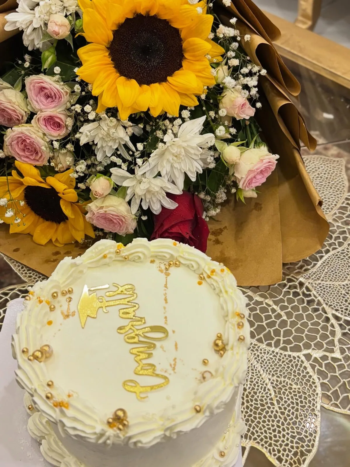 Congratulations cake in gold script with a sunflower bouquet