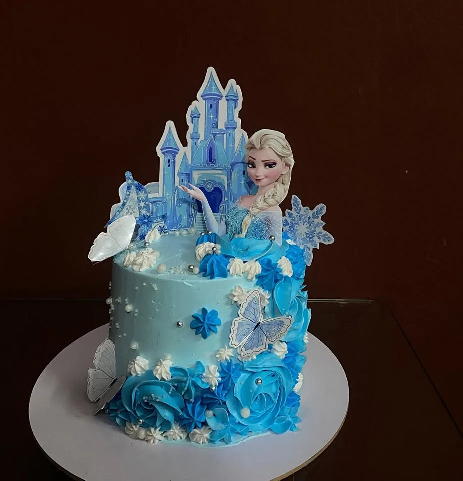 Frozen themed birthday cake with an ice castle topper, Elsa and blue buttercream roses