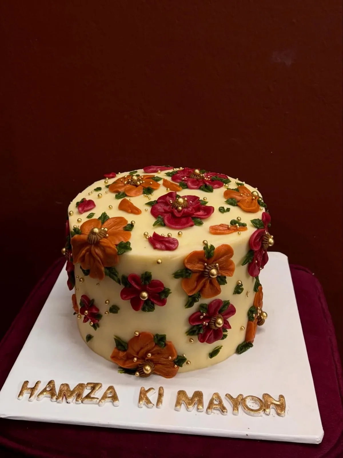 Mayon cake with bright fondant flowers and gold accents