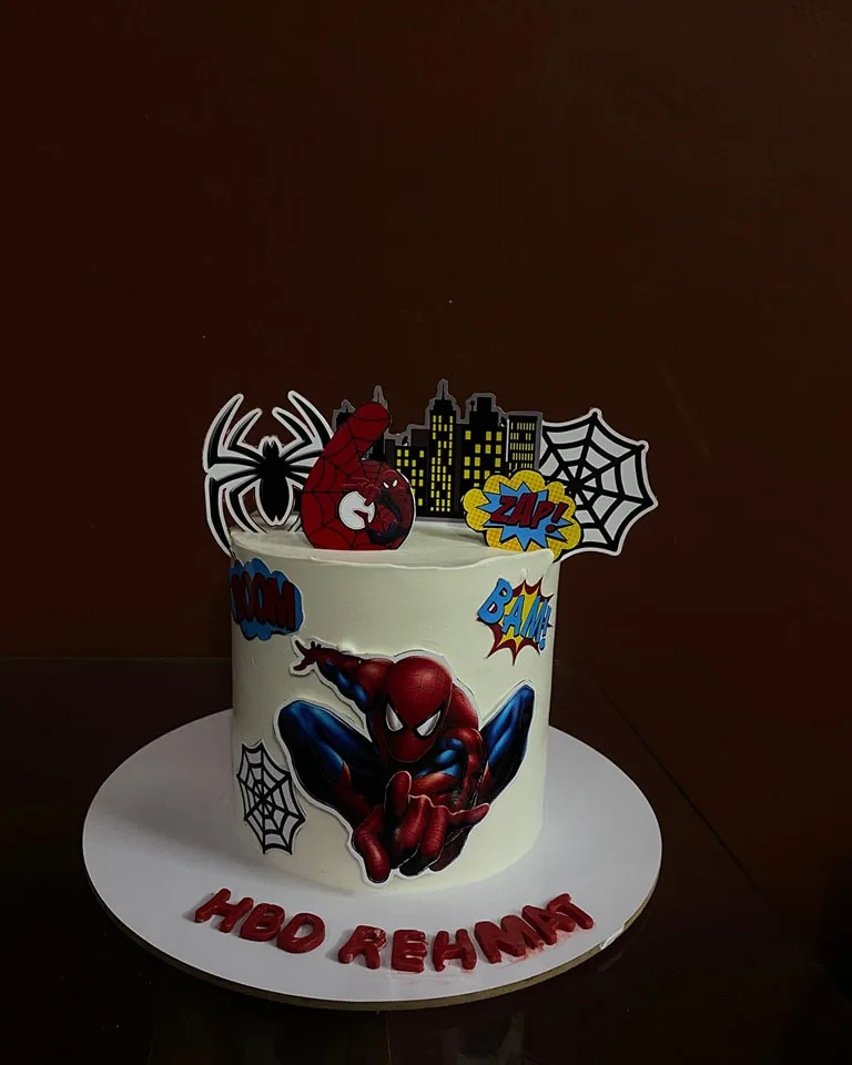 Spider-Man themed birthday cake with comic-style toppers and a city skyline