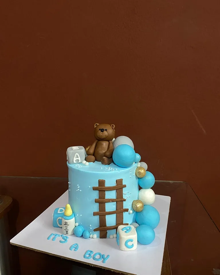 Blue It's A Boy welcome cake with a fondant teddy bear, ladder and balloons