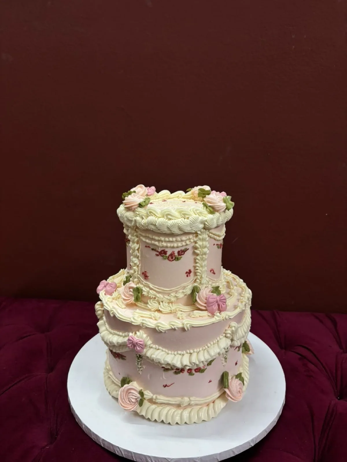 Two-tier pink vintage cake with piped roses, bows and lace detailing